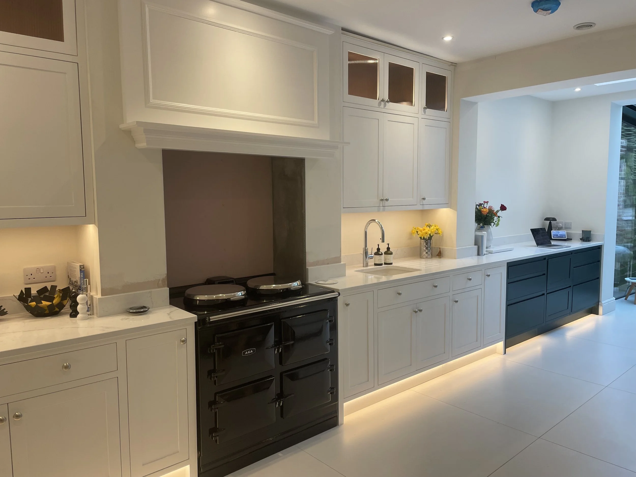 Modern kitchen with white cabinets, black stove, and decorative flowers on counter.