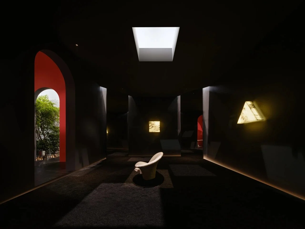 Dark interior room with a modern white chair near the center, illuminated by natural light from rectangular and irregularly shaped windows on black walls, with a view of trees outside.