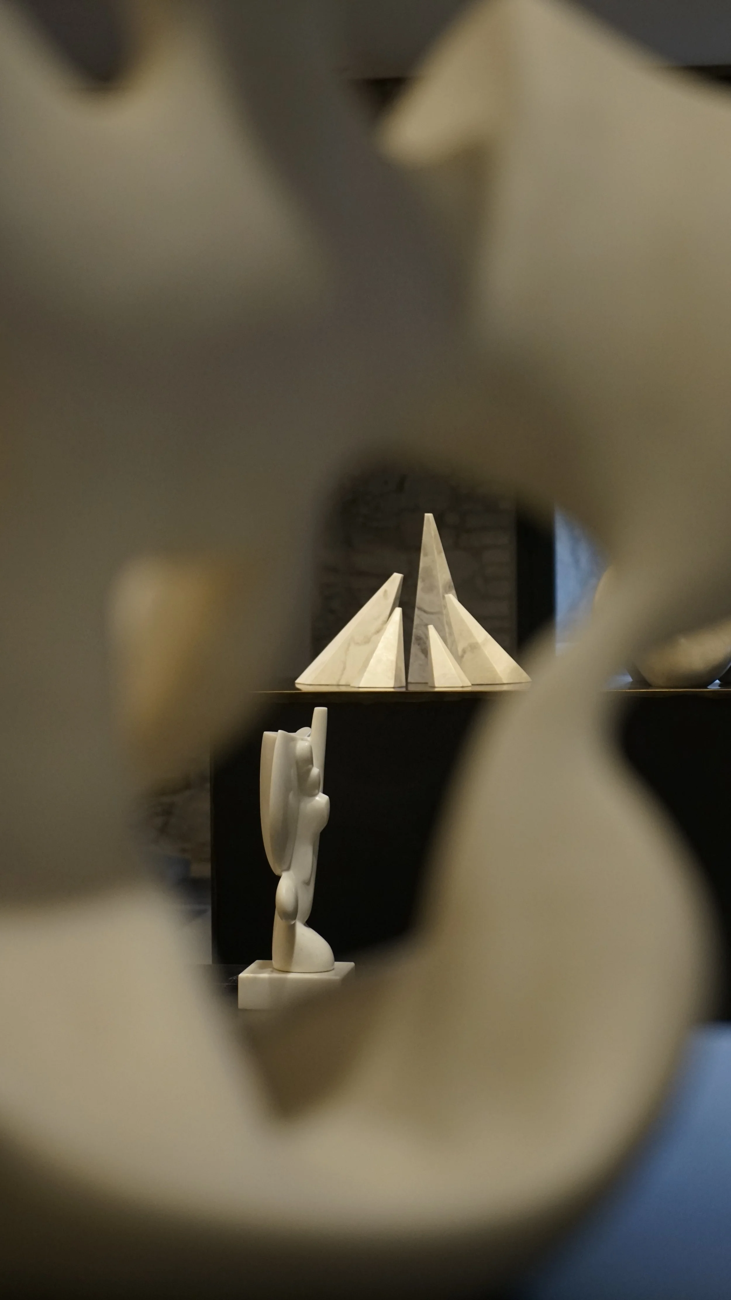 Various abstract sculptures in a room, viewed through a frame of abstract shapes in the foreground.