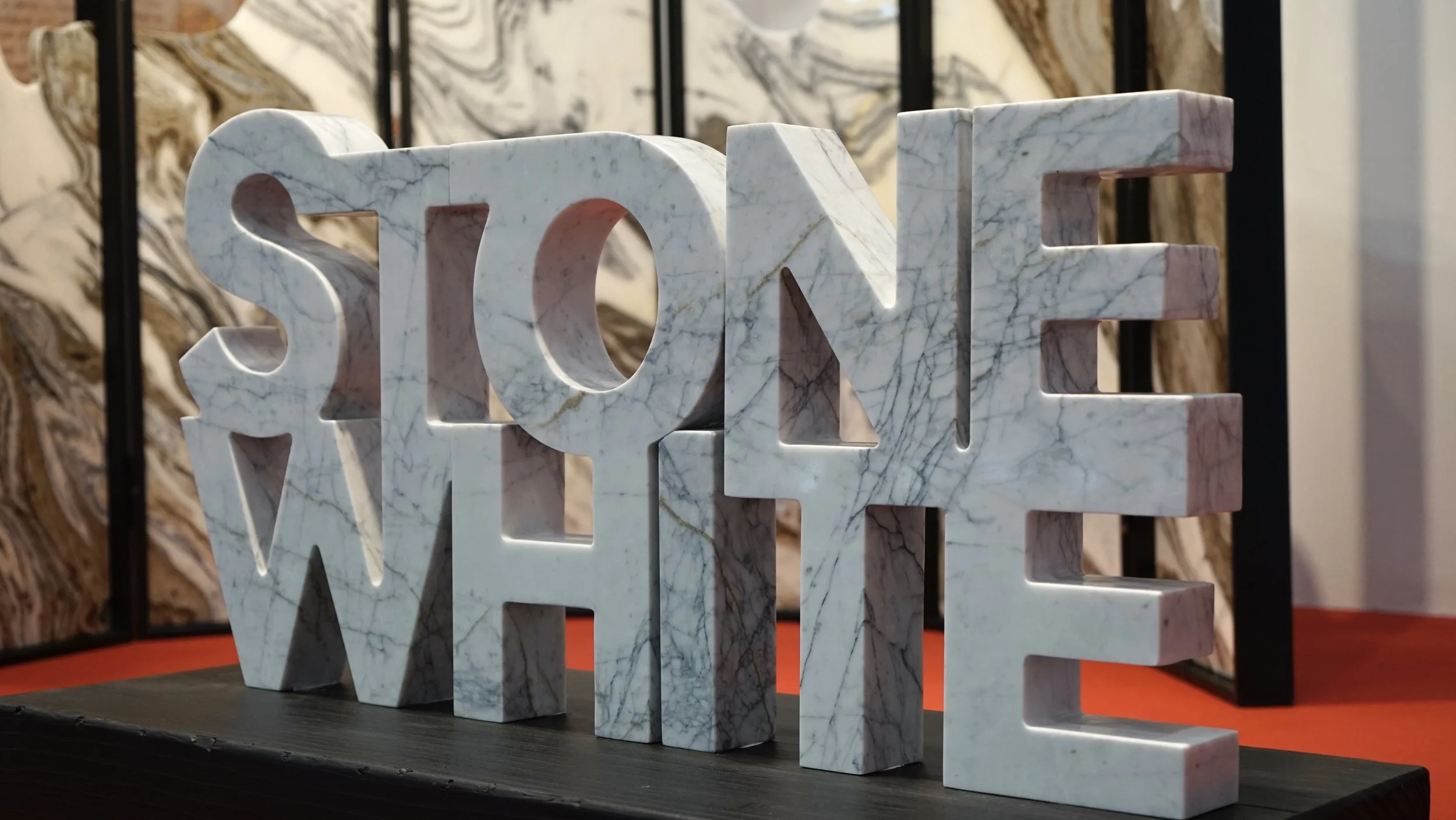 Marble decorative sculpture spelling the word 'LOVE' with the letters arranged to form a three-dimensional sign on a dark surface.