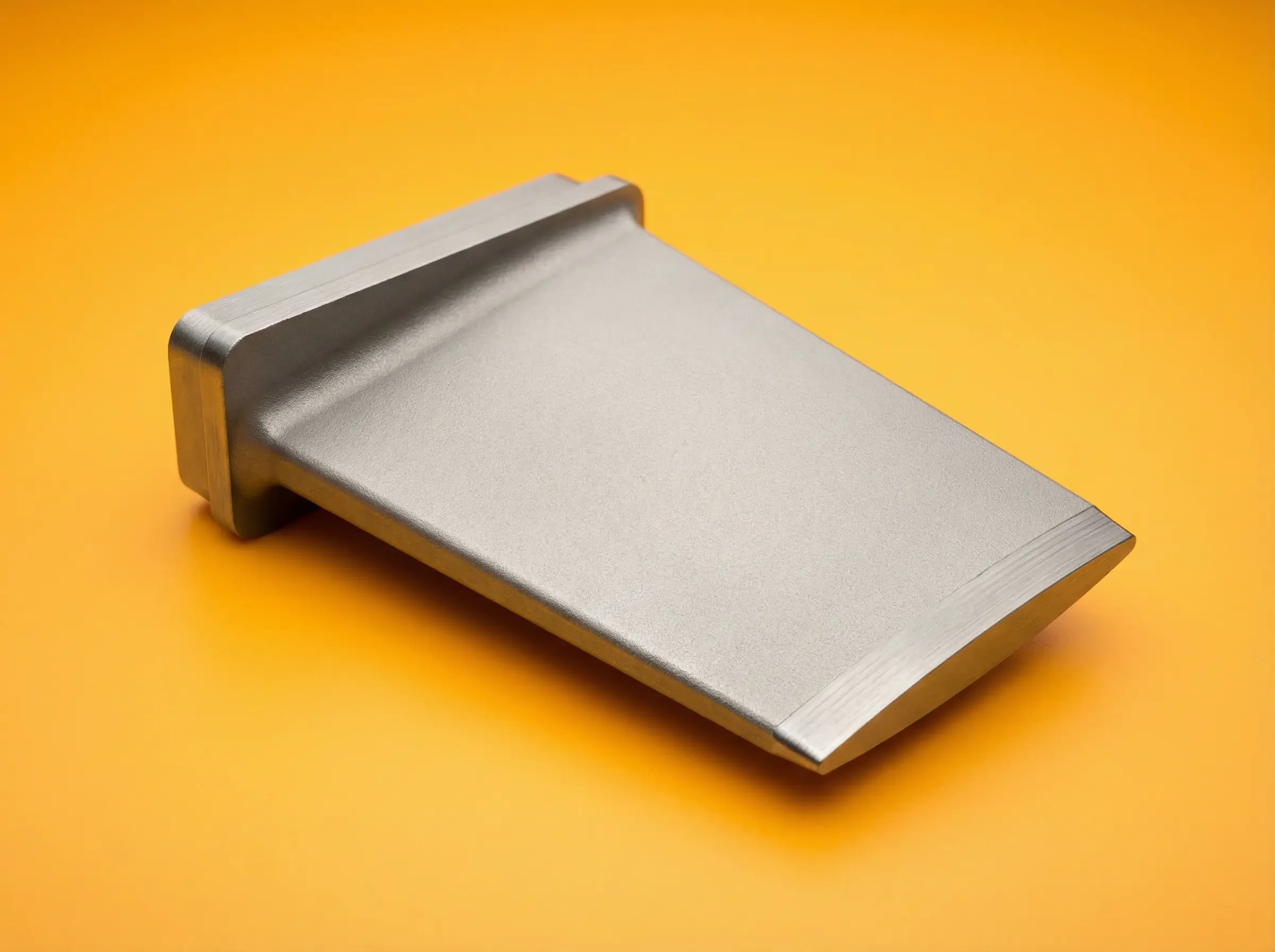 A metallic hand planer tool resting on a yellow surface.
