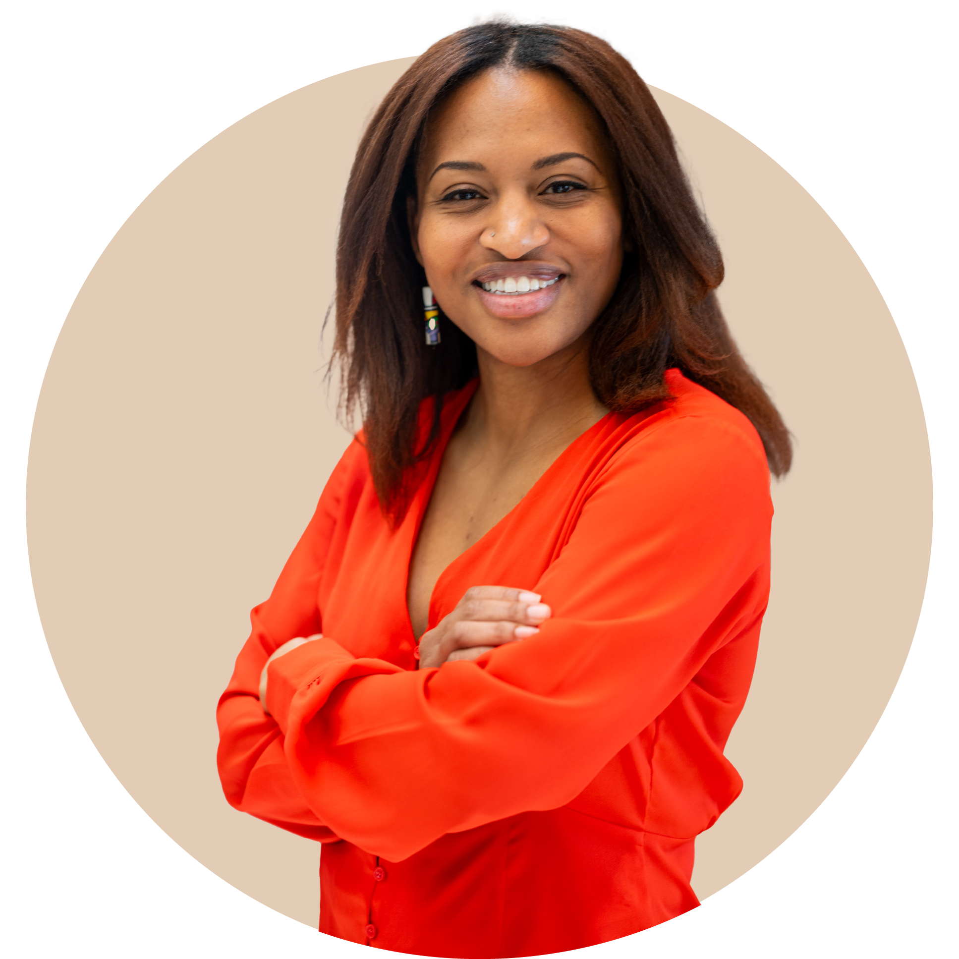 A smiling woman with shoulder-length hair, wearing a bright orange blouse, standing with arms crossed against a beige background.