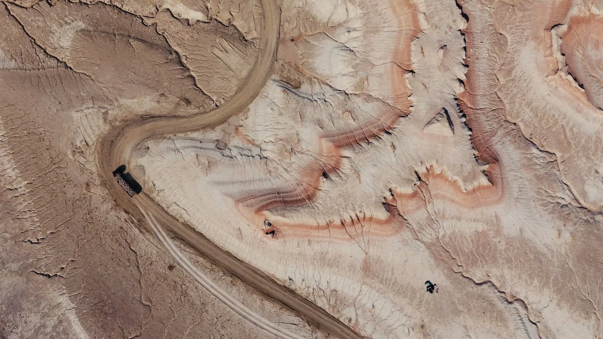 Aerial view of a desert with winding dirt roads and colorful rock formations.