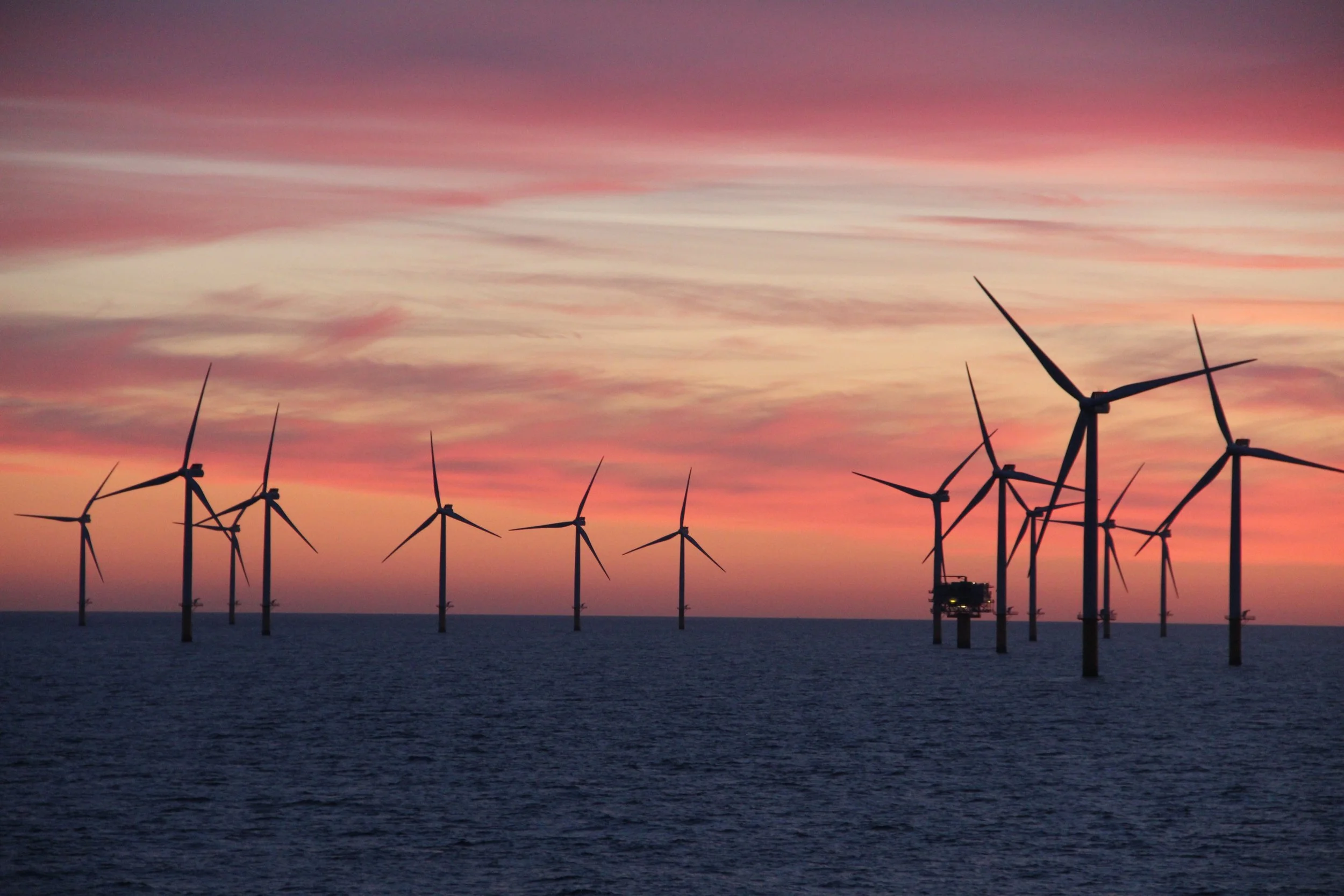 Offshore wind turbines at sunset with colorful sky and calm water