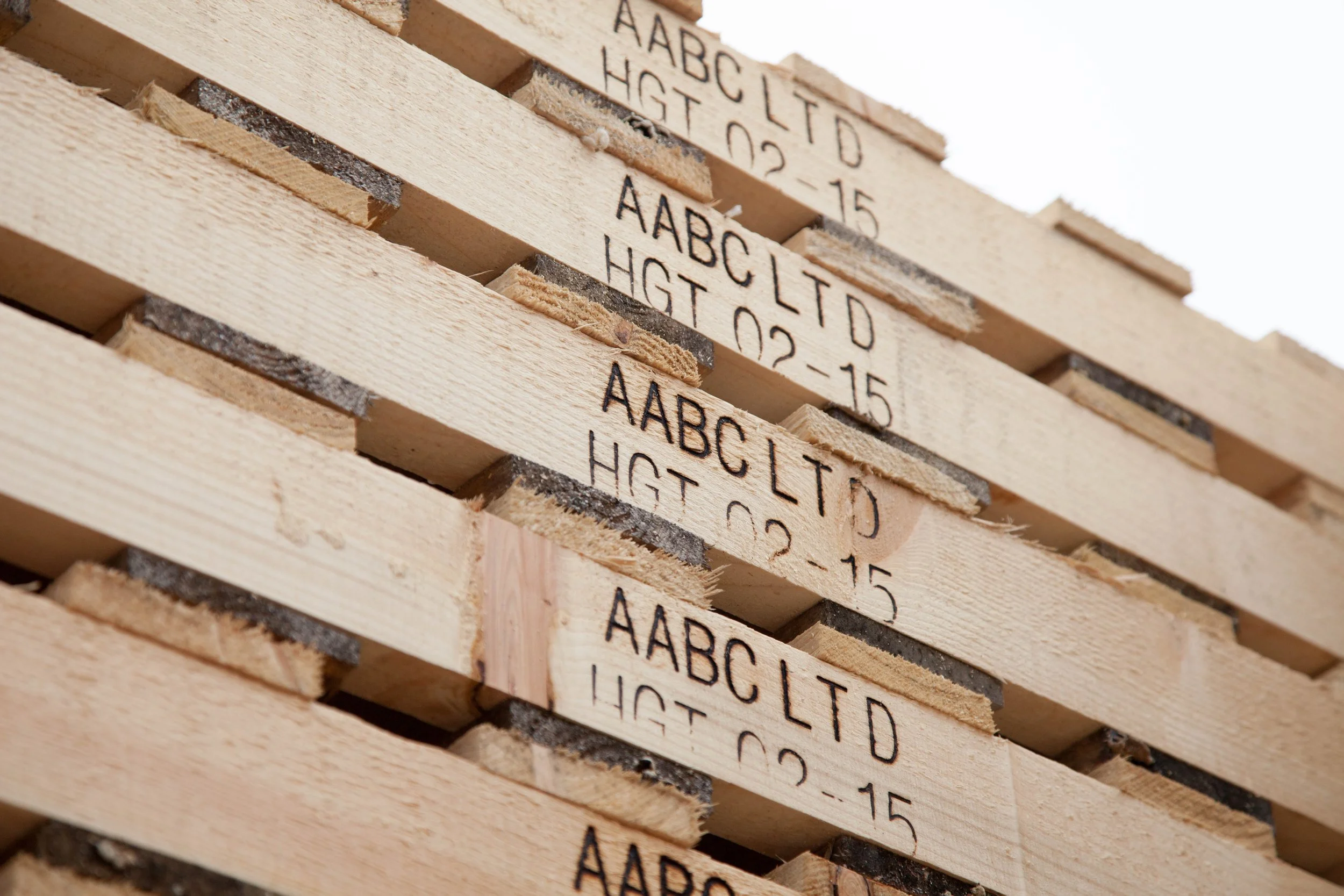 Stacked wooden pallets with black stencil markings including letters and numbers.
