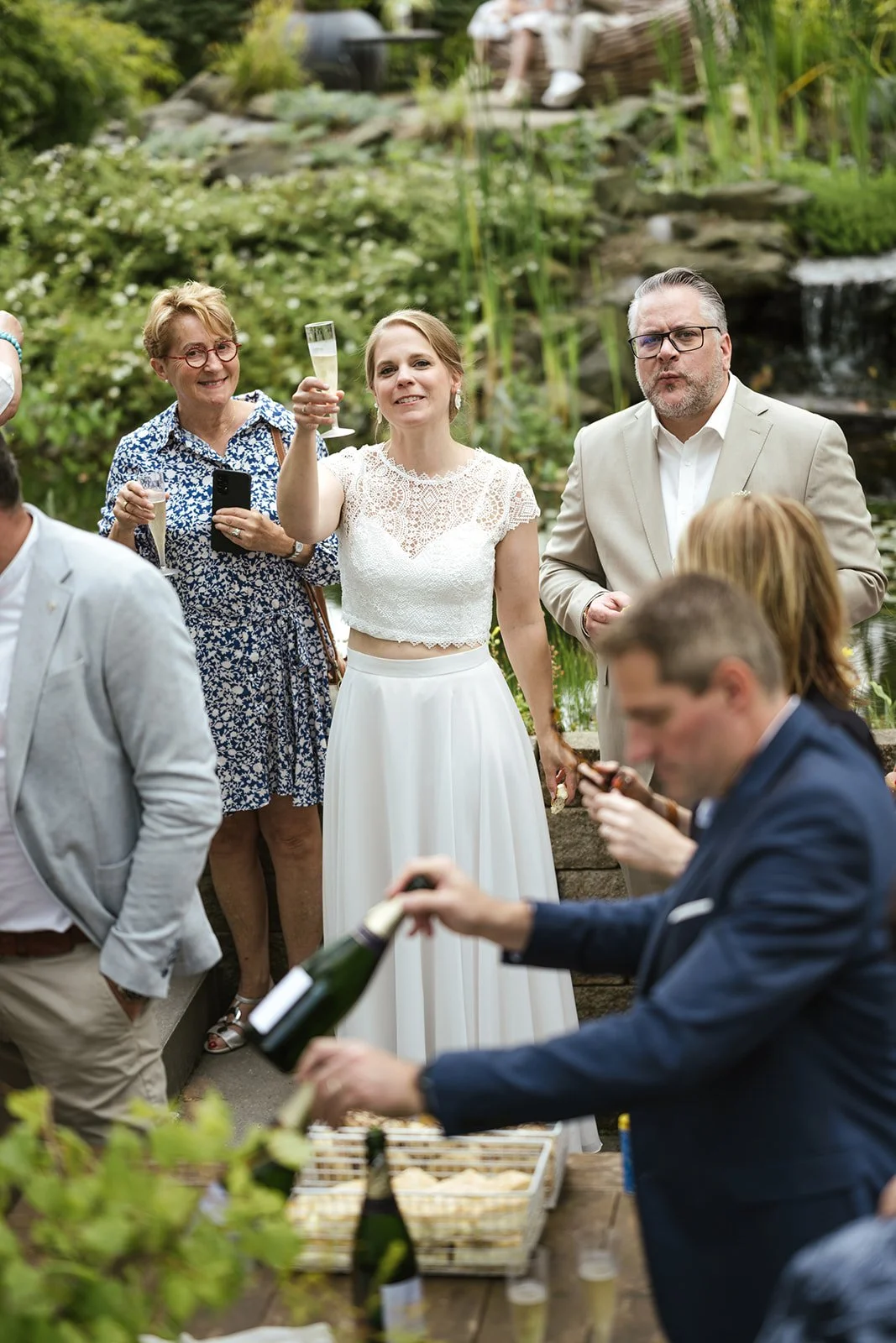 Braut und Bräutigam trinken Champagne nach der Trauung im Park.