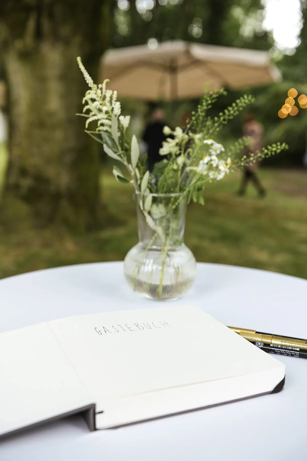 Gästebuch und Tischdeko am Stehtisch im Park nach der Trauung.