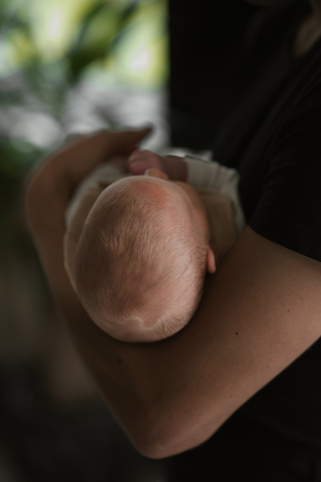 Nahaufnahme eines neugeborenen Babys, das an der Brust einer Person saugt, während diese es hält.