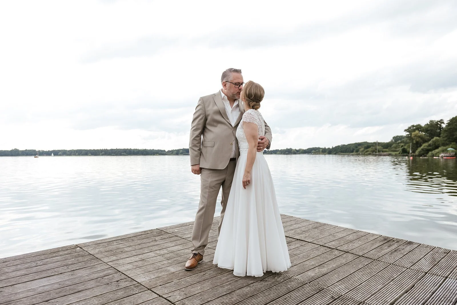 Braut und Bräutigam am See, stehen am Steg.