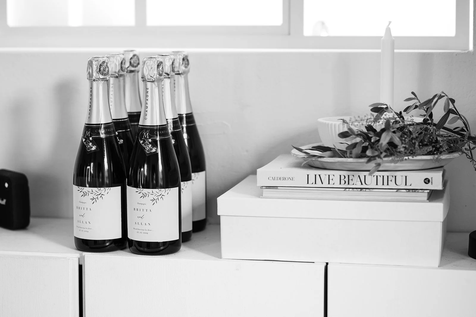 Detailaufnahme im Raum. Champagne Flaschen stehen neben Dekoelementen und Bücher.