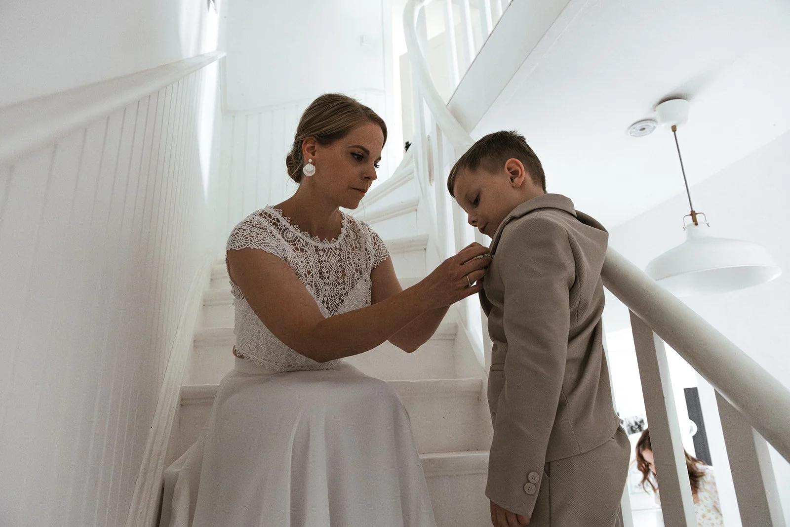 Braut zieht ihren kleinen Sohn an. Sie sitzen auf der Treppe.