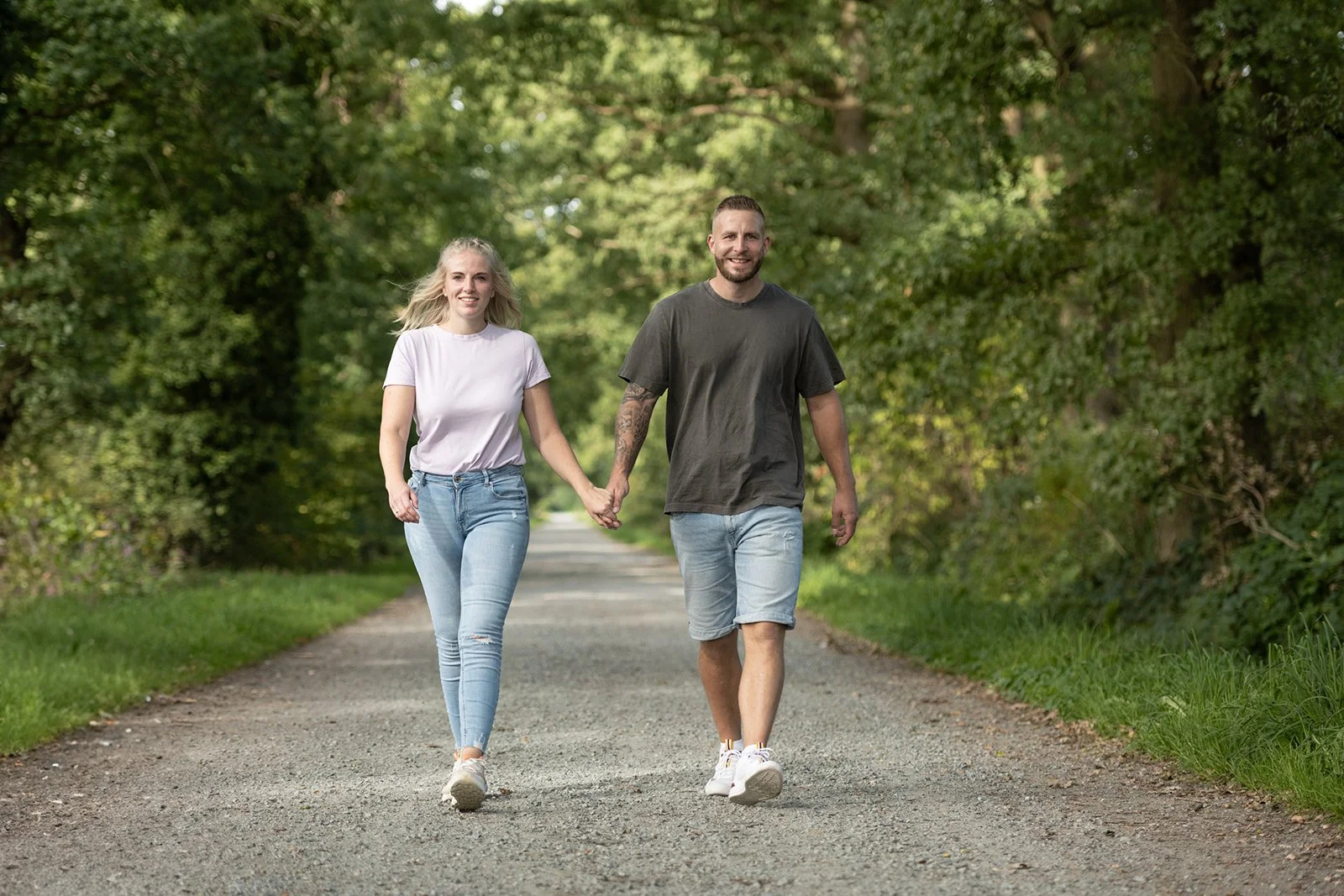 Paar läuft Richtung Kamera auf einem Waldweg.