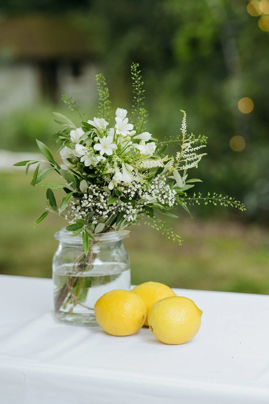 Hochzeitsdeko auf dem Tisch, Blumenstrauß und Zitronen. Hintergrund ist unscharf und zeit den Garten.
