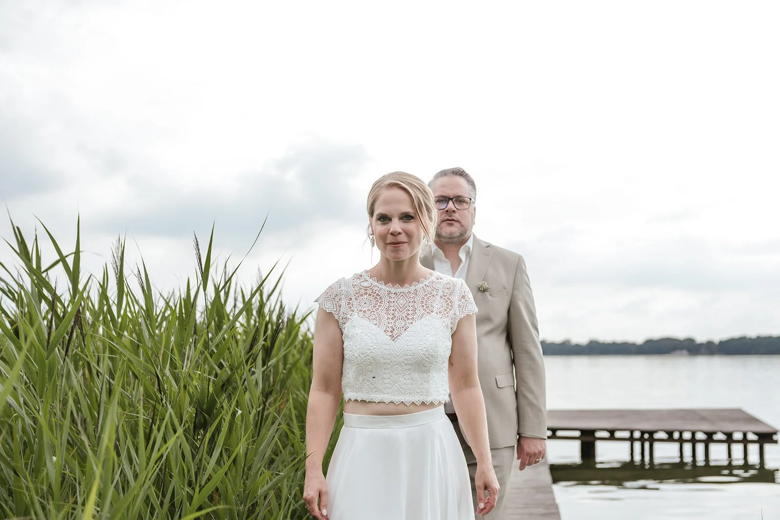 Braut un Bräutigam stehen am Steg am See.