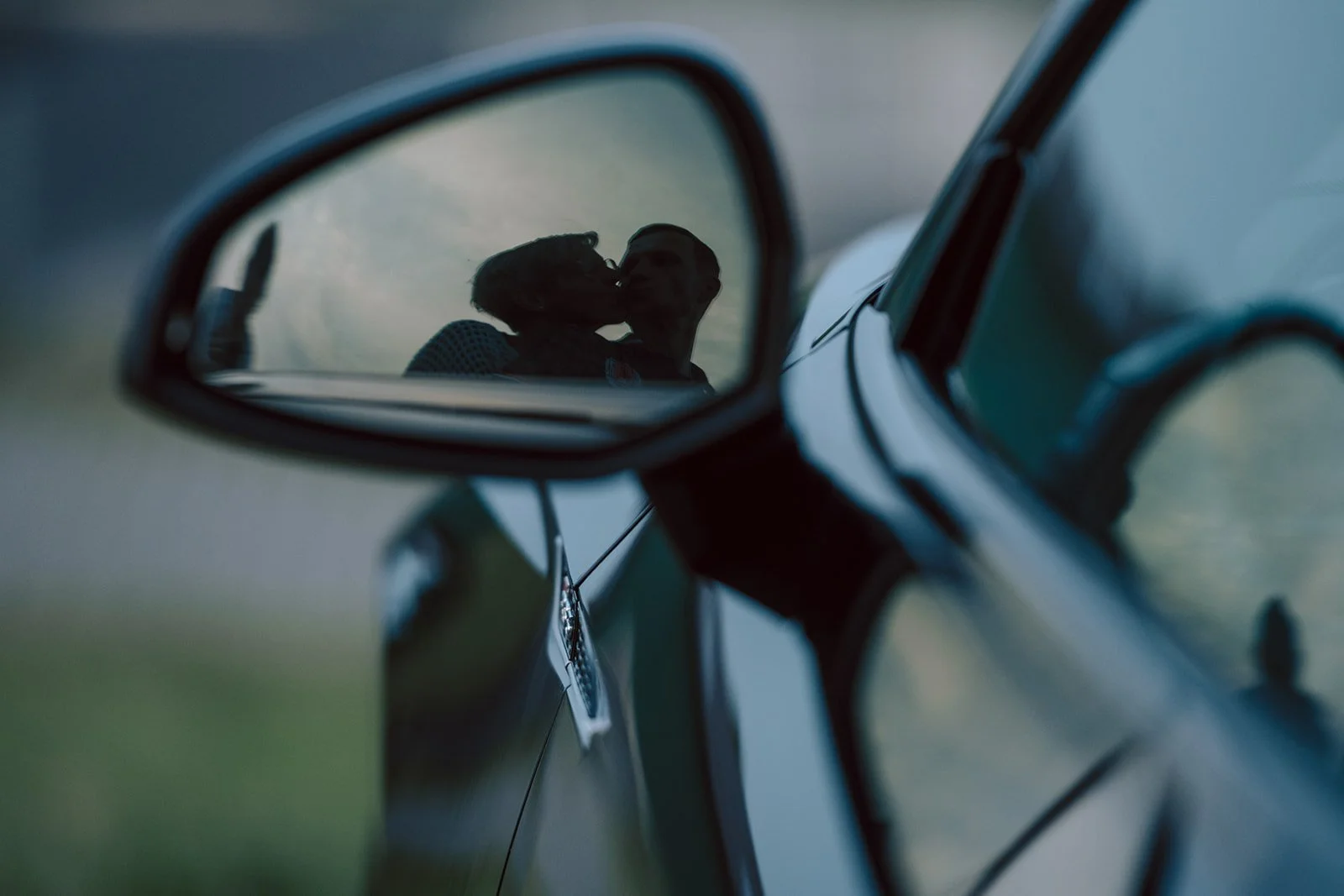 Zwei Personen küssen sich, gesehen im Autospiegel
