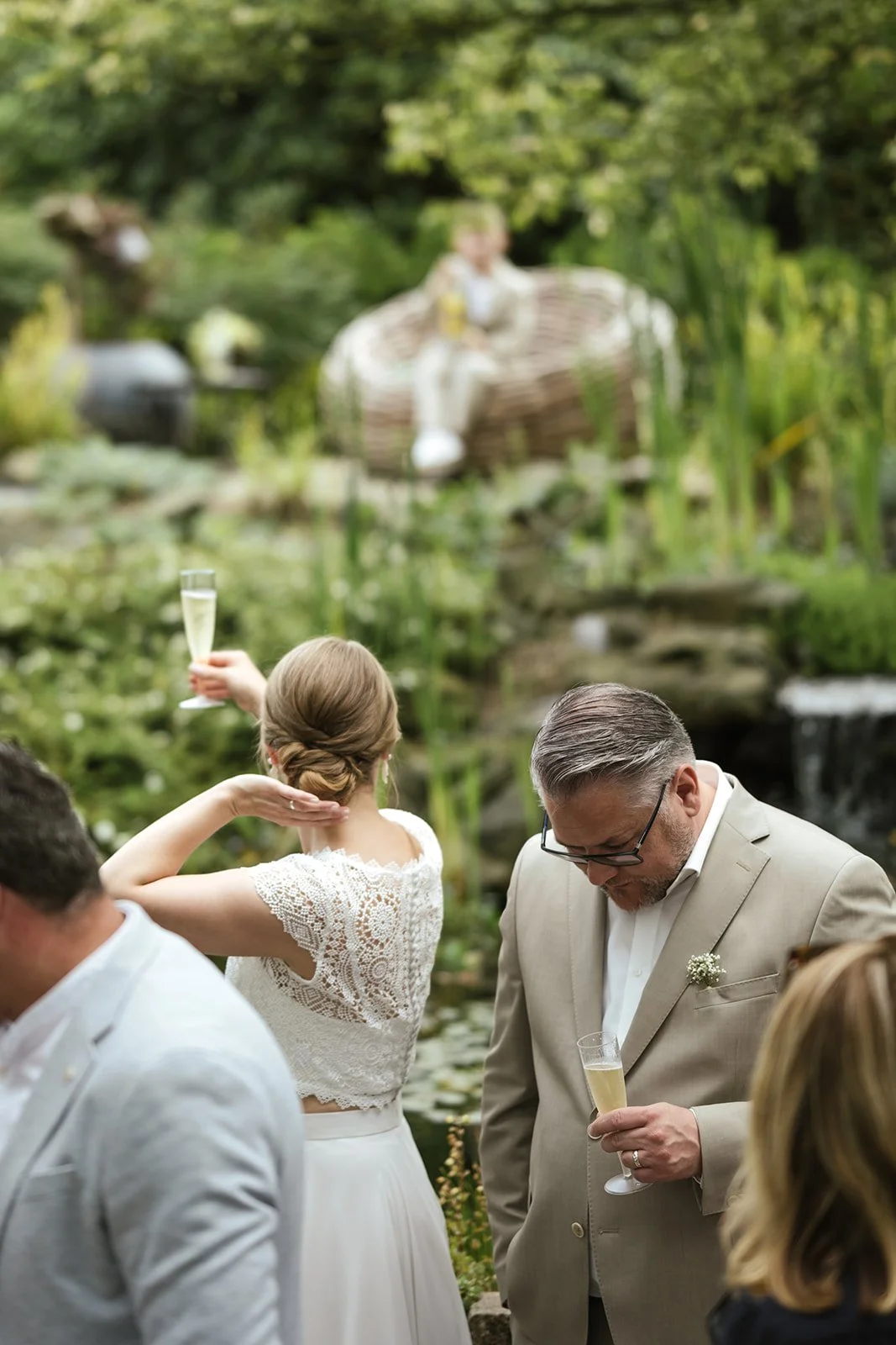 Hochzeit im Park der Gärten in Oldenburg, Braut hält Sektglas in der Hand.