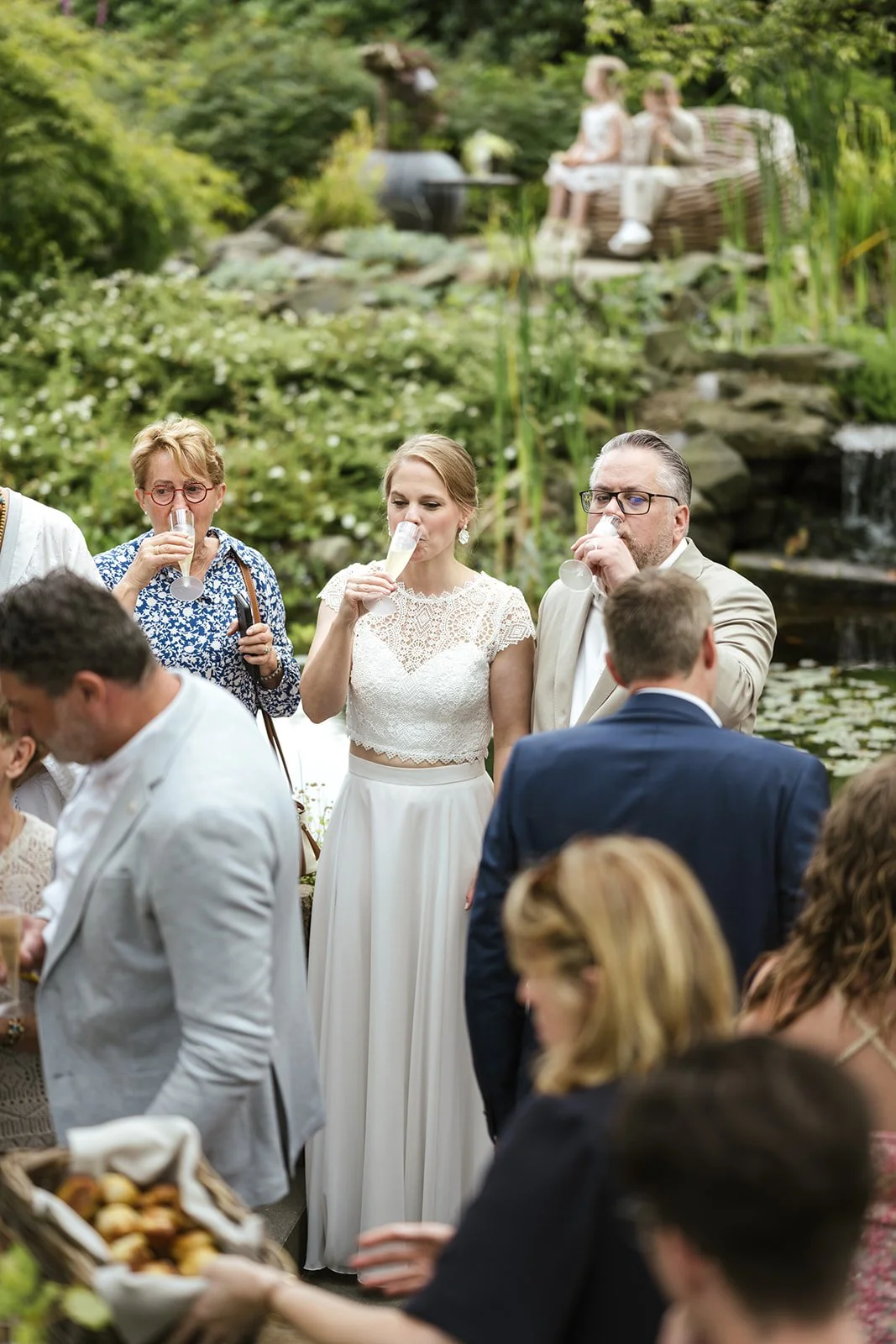 Braut und Bräutigam im Park während dem Sektempfang. Sie halten in der Hand Champagner.