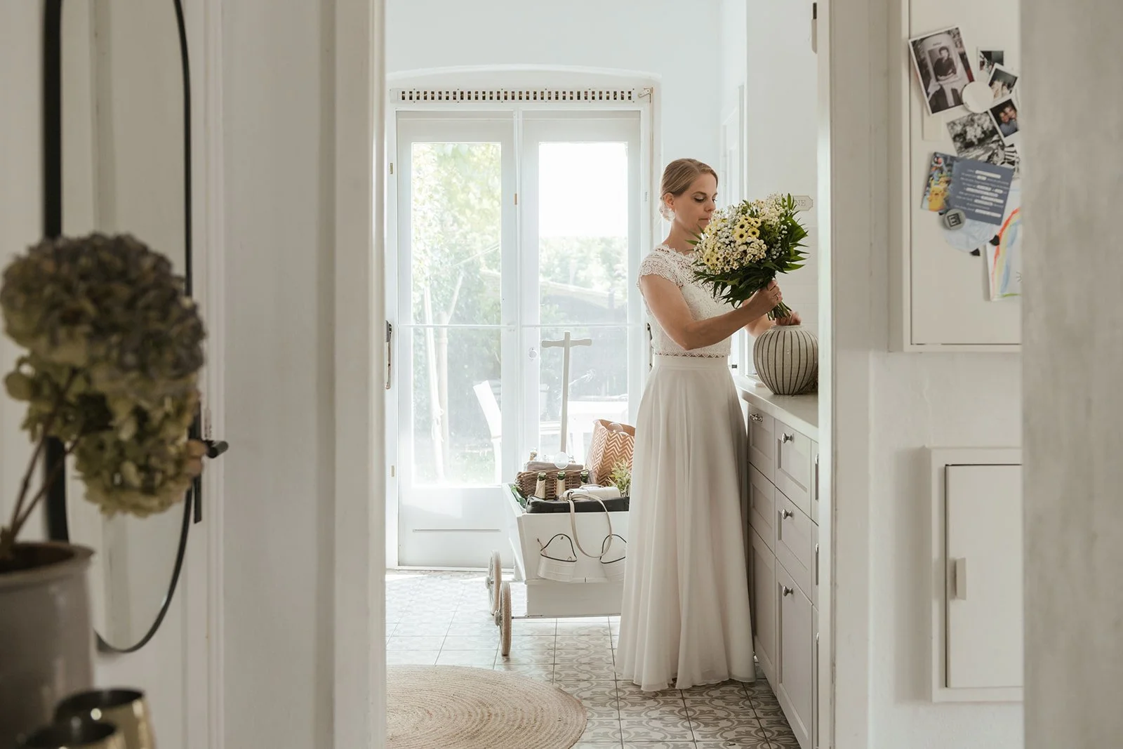 Braut steht in der Küche und stellt ihren Blumenstrauß in die Vase.