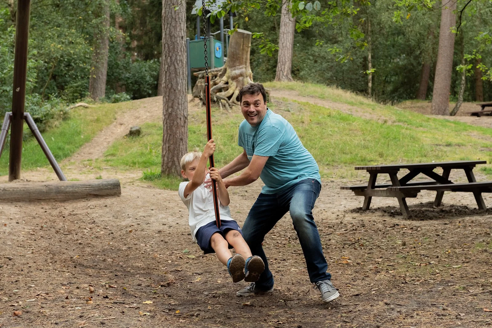 Ein Mann schiebt einen Jungen auf einer Schaukel im Park.
