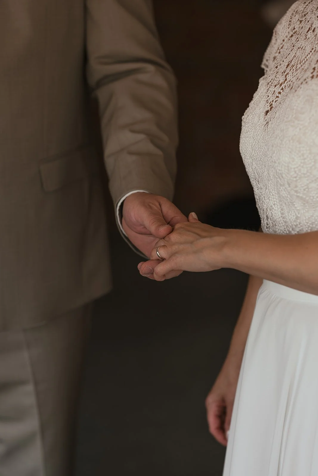 Braut und BRäutigem halten Hände. Ehering ist an dem Finger zu sehen.