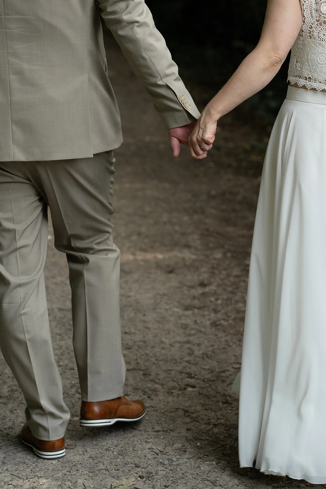 Braut und Bräutigam halten Hände während Spatziergang.