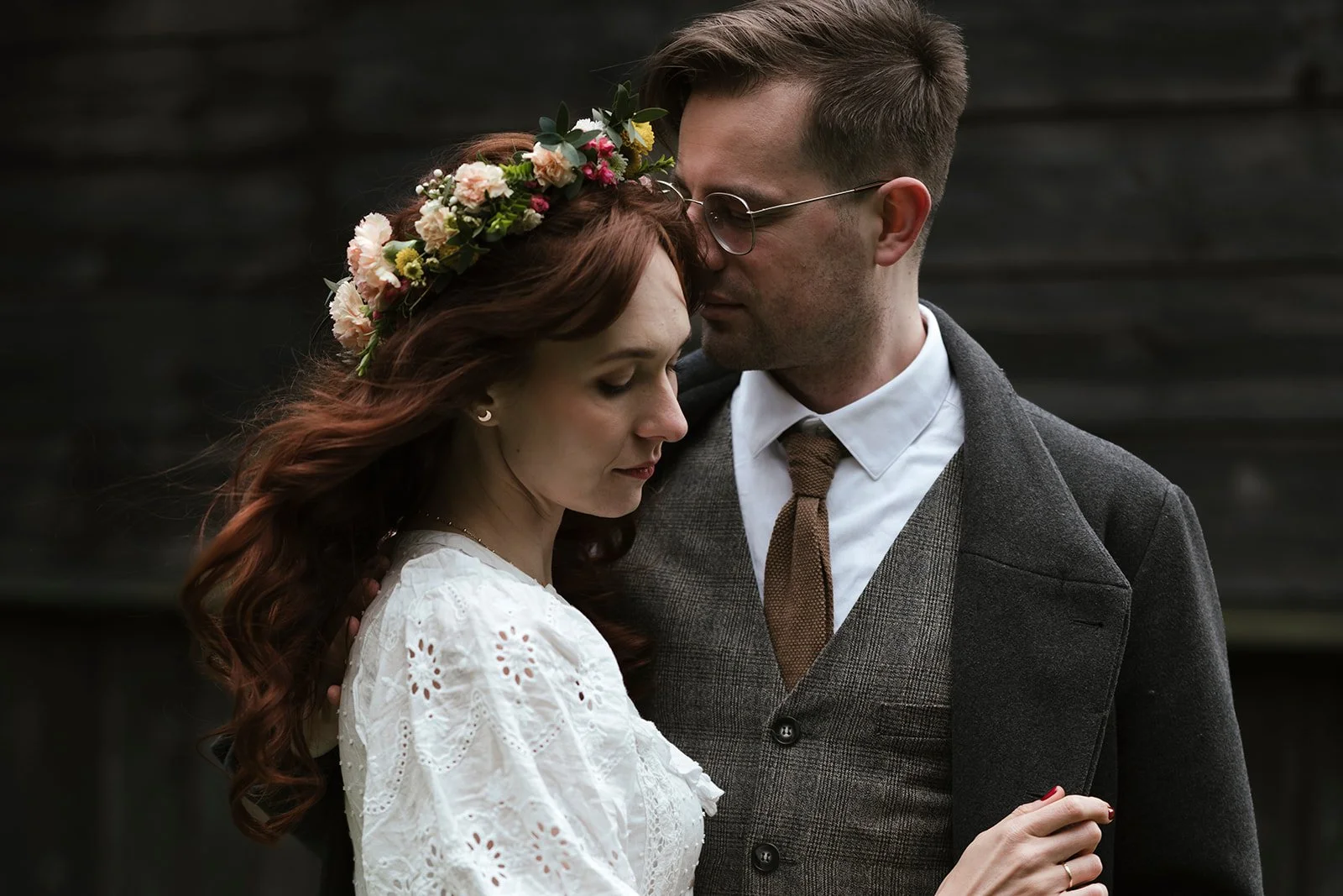 Ein Paar im Vintage-Outfit steht eng beieinander, die Frau trägt ein Blumenkranz im Haar, beide haben die Augen geschlossen.