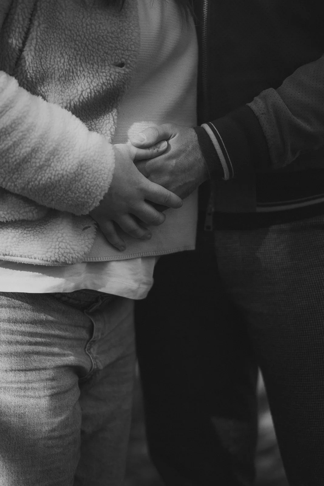 Zwei Menschen halten sich an den Händen, Nahaufnahme in Schwarz-Weiß.