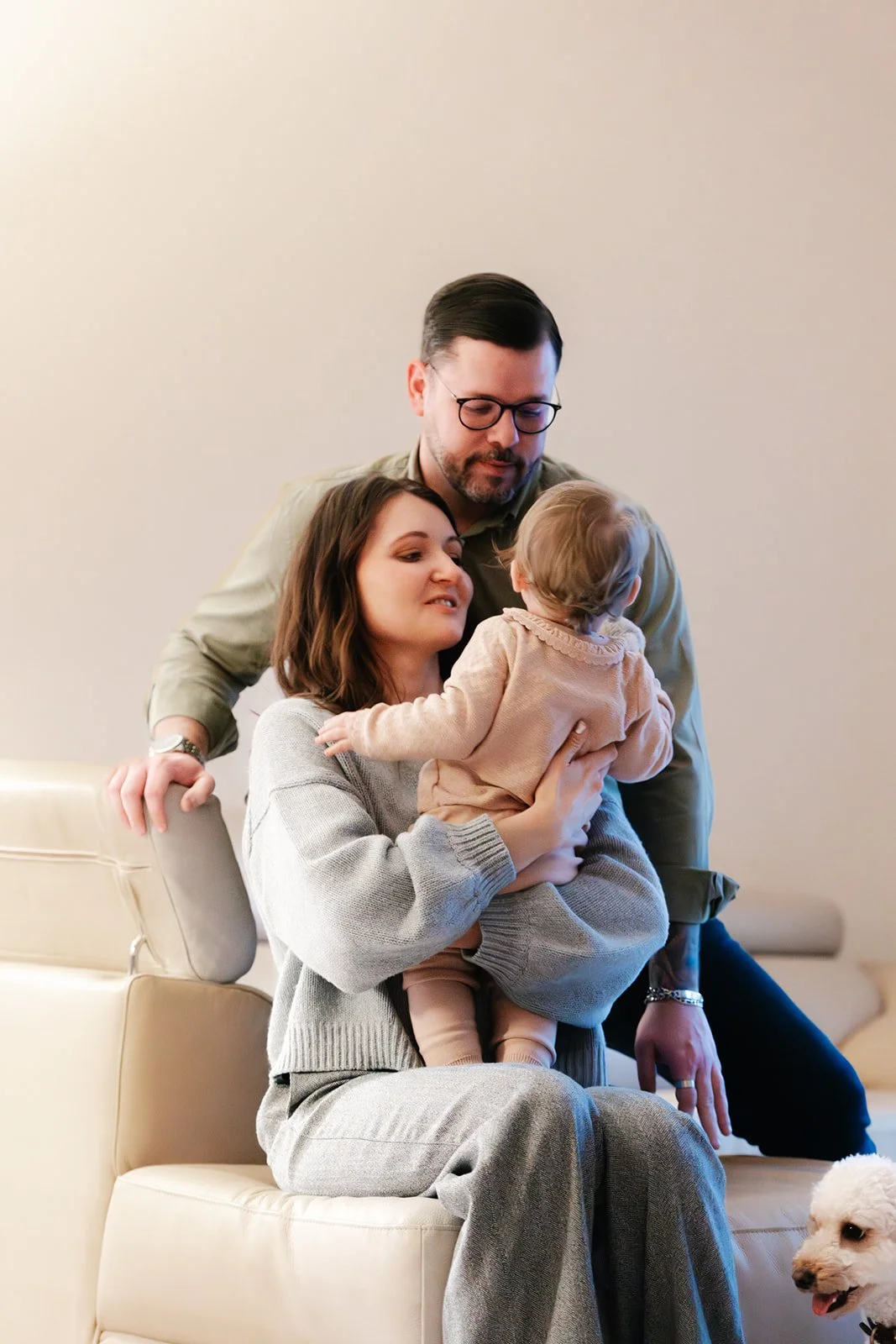 Junde Familie zuhause mit Kleinkind kuscheln auf dem Sofa