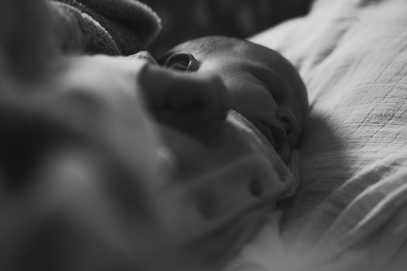 Schwarz-weiß-Foto eines schlafenden Babys mit geschlossenen Augen auf einem Kissen.