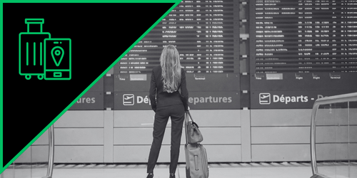A woman with long hair standing at an airport departure information board, holding a suitcase.