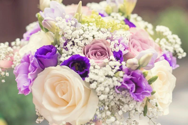 Close-up of a bouquet with white roses, purple lisianthus, and baby's breath.