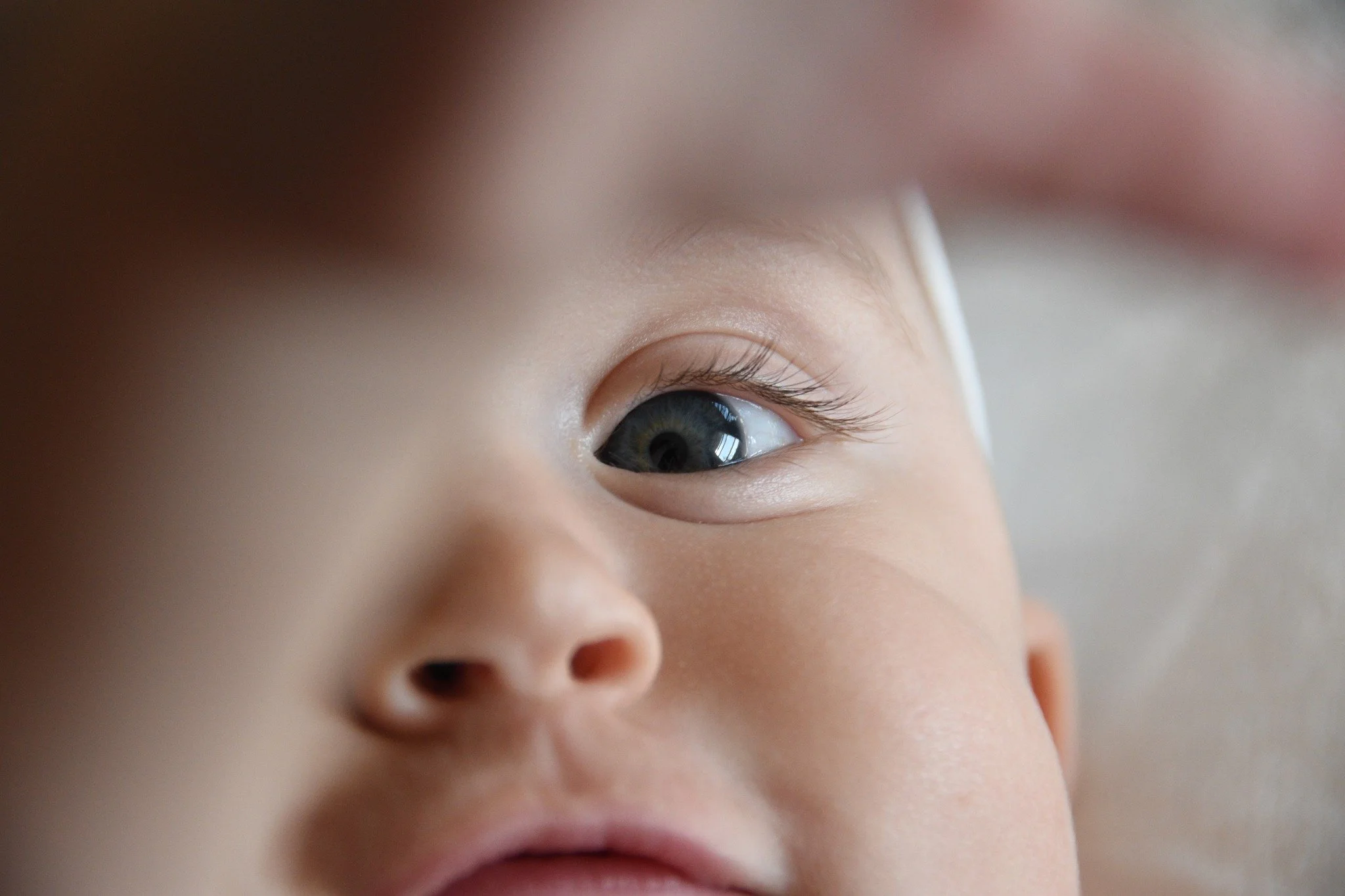 Close-up of a baby's face, focusing on the right eye, with smooth skin and light-colored eyelashes.