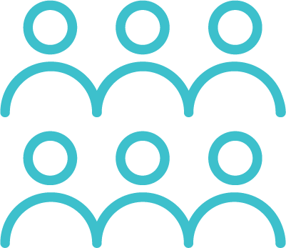 Two people sitting at a table with a laptop, notebook, pen, glass of water, and decorative items including a white vase with calla lilies and a wooden panel in the background.