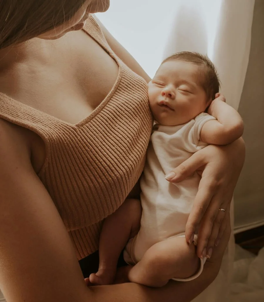Bébé endormi contre la poitrine de sa maman après l'allaitement.