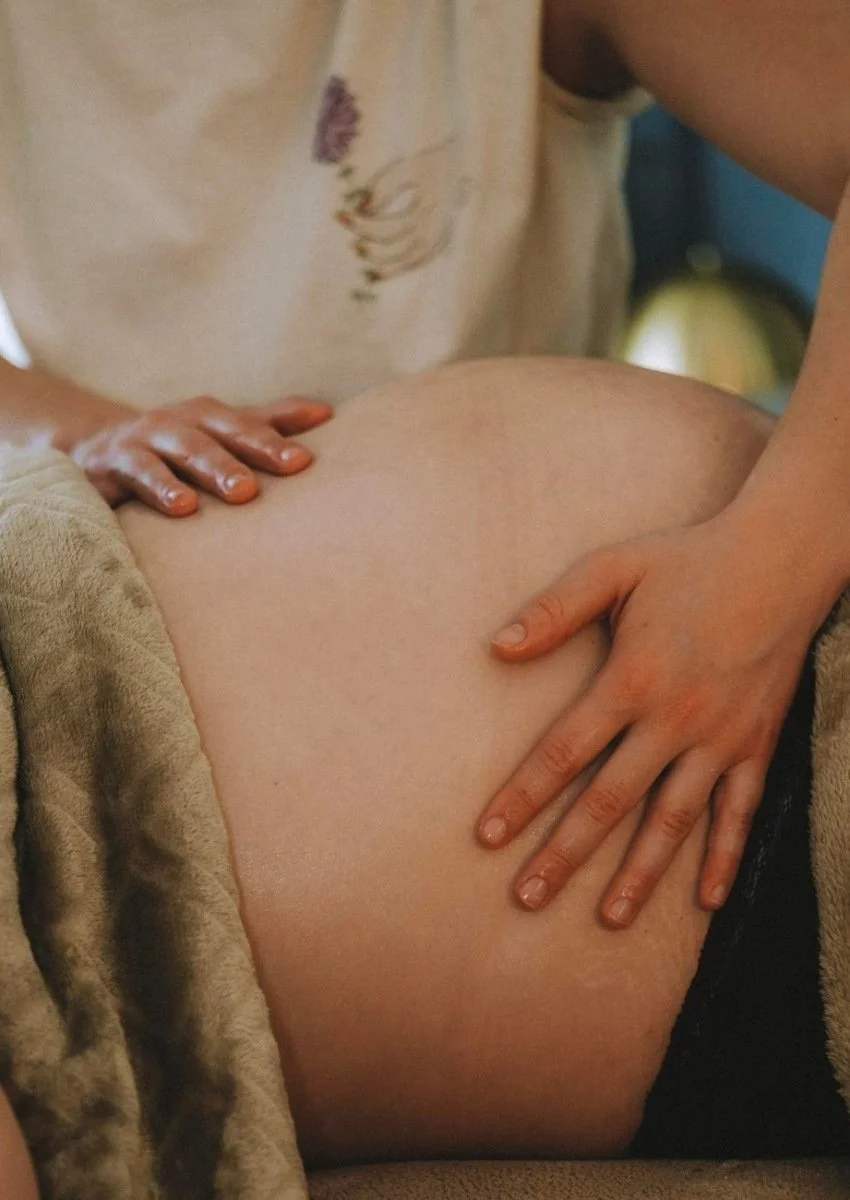 Chloé Tassin réalisant un massage relaxant sur le ventre d'une femme enceinte