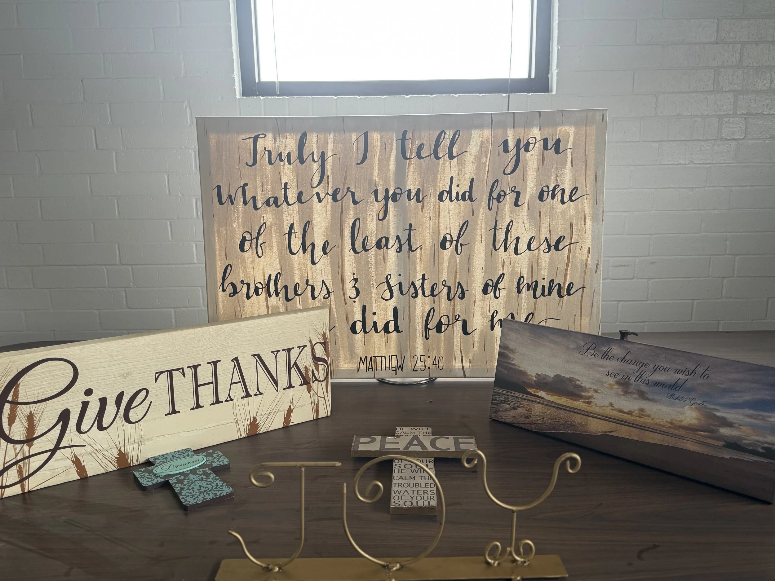 Decorative inspirational signs and signs with quotes on a table, with a window in the background.