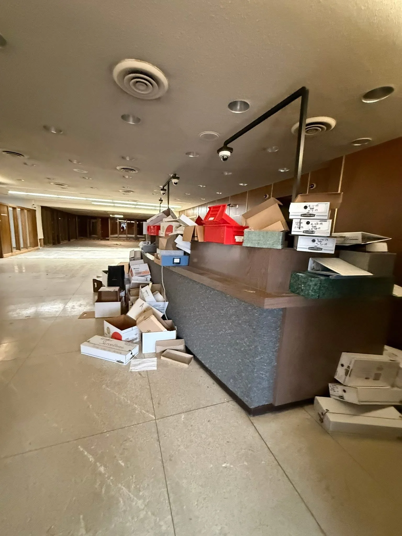 Empty restaurant or hotel lobby with scattered and overflowing cardboard boxes, some stacked on counter and some on the floor.