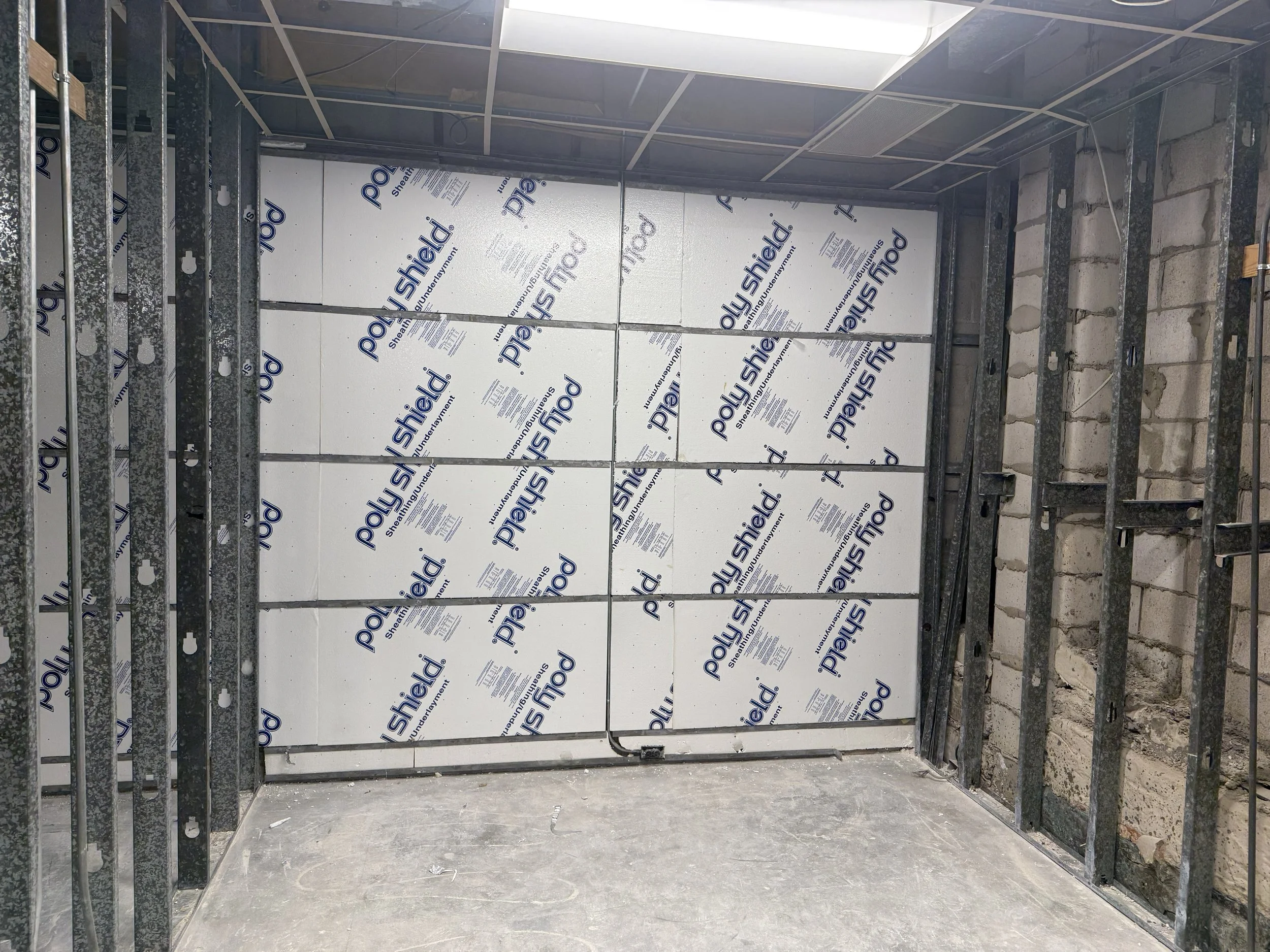 Construction site interior showing metal framing and insulation panels on the back wall.