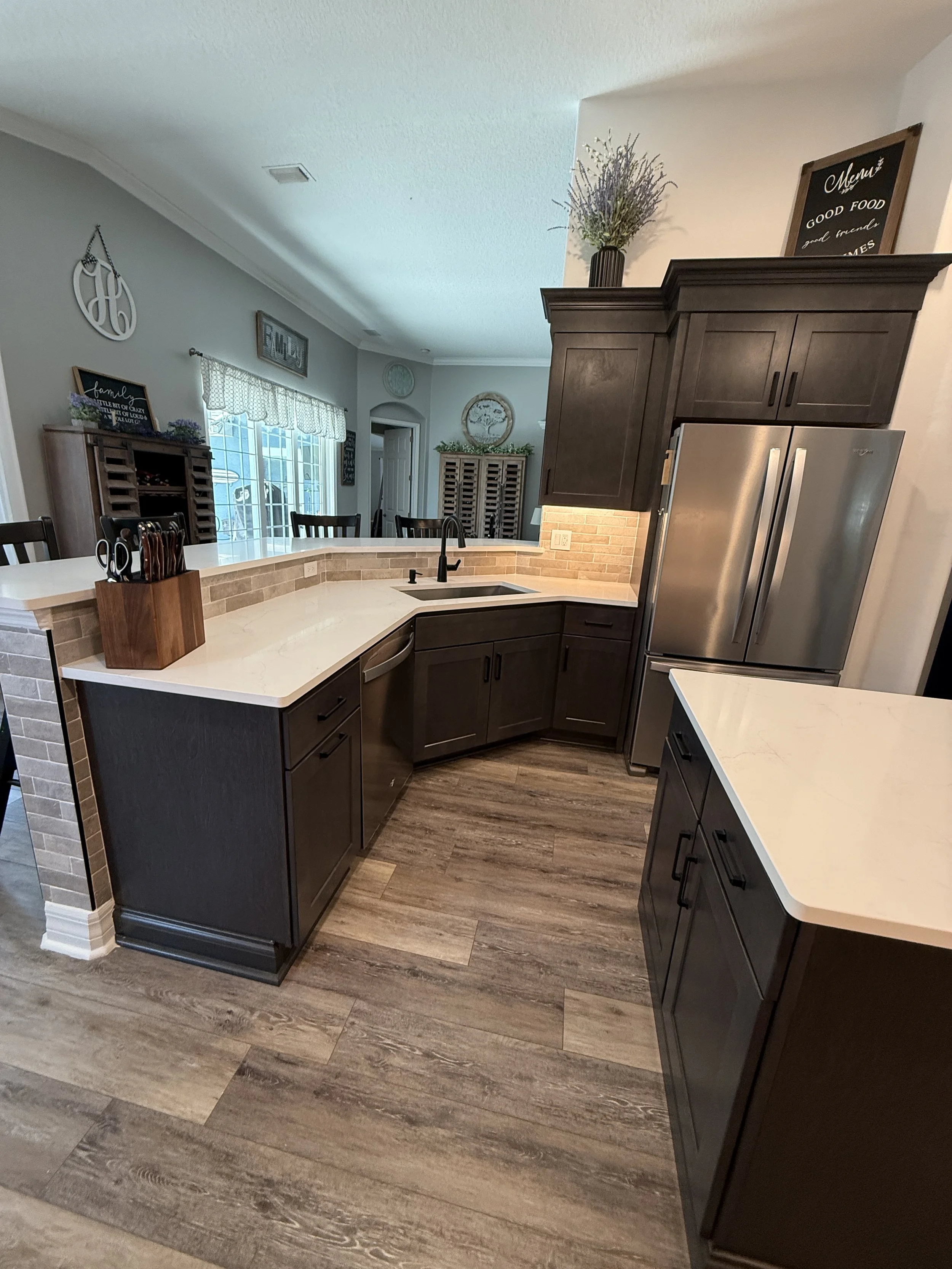A kitchen Remodel we completed in 2026 in Ormond Lakes Neighborhood in Ormond Beach Florida. With dark custom wooden cabinets, quartz countertops, Backsplash tile, LED dimmable lighting for under cabinet lighting. Interior Paint Job