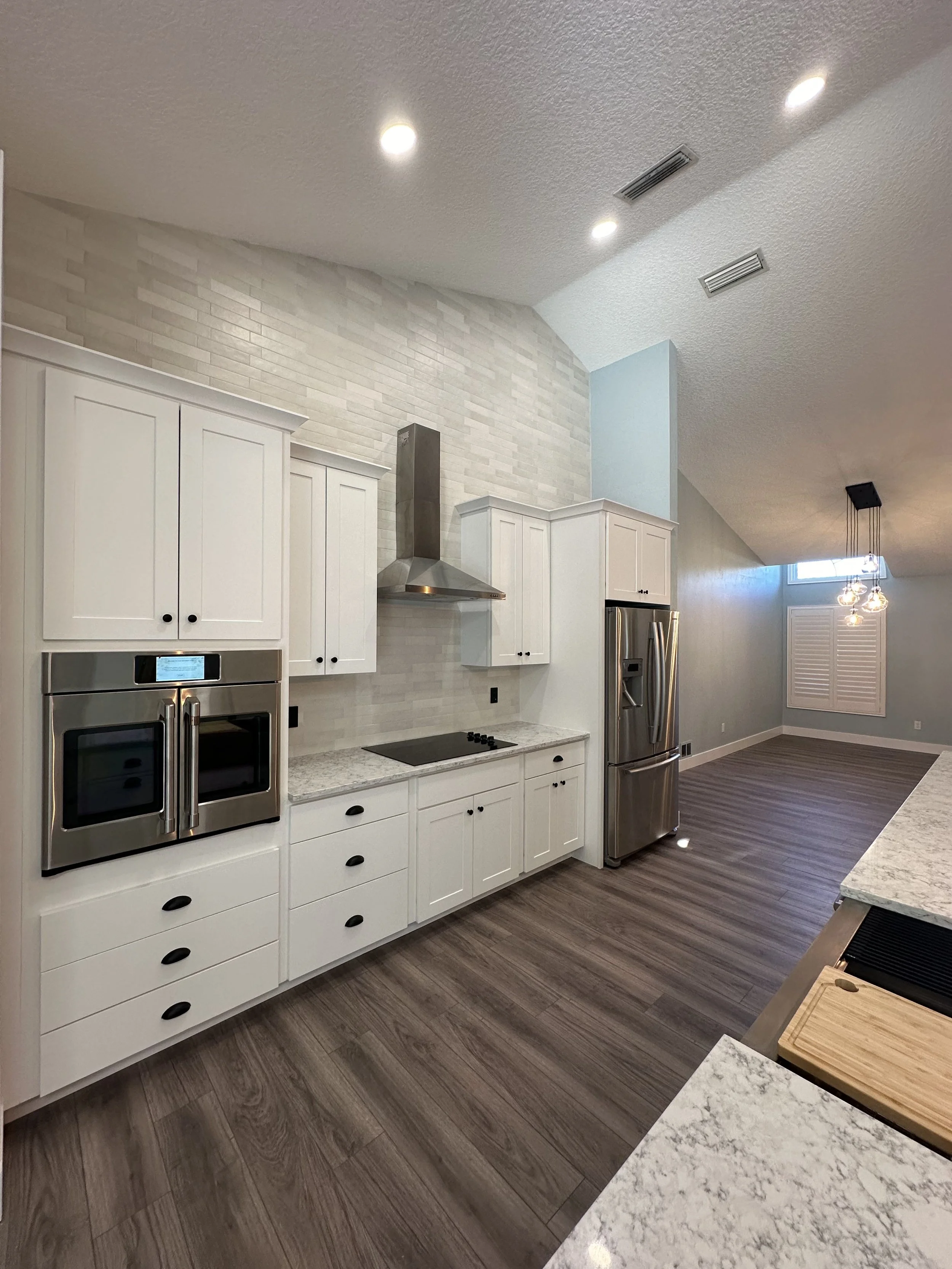 New Modern kitchen with white cabinets, stainless steel appliances, a stove, and laminate wood flooring. we completed in Hunters Ridge Neighborhood in Ormond Beach Florida