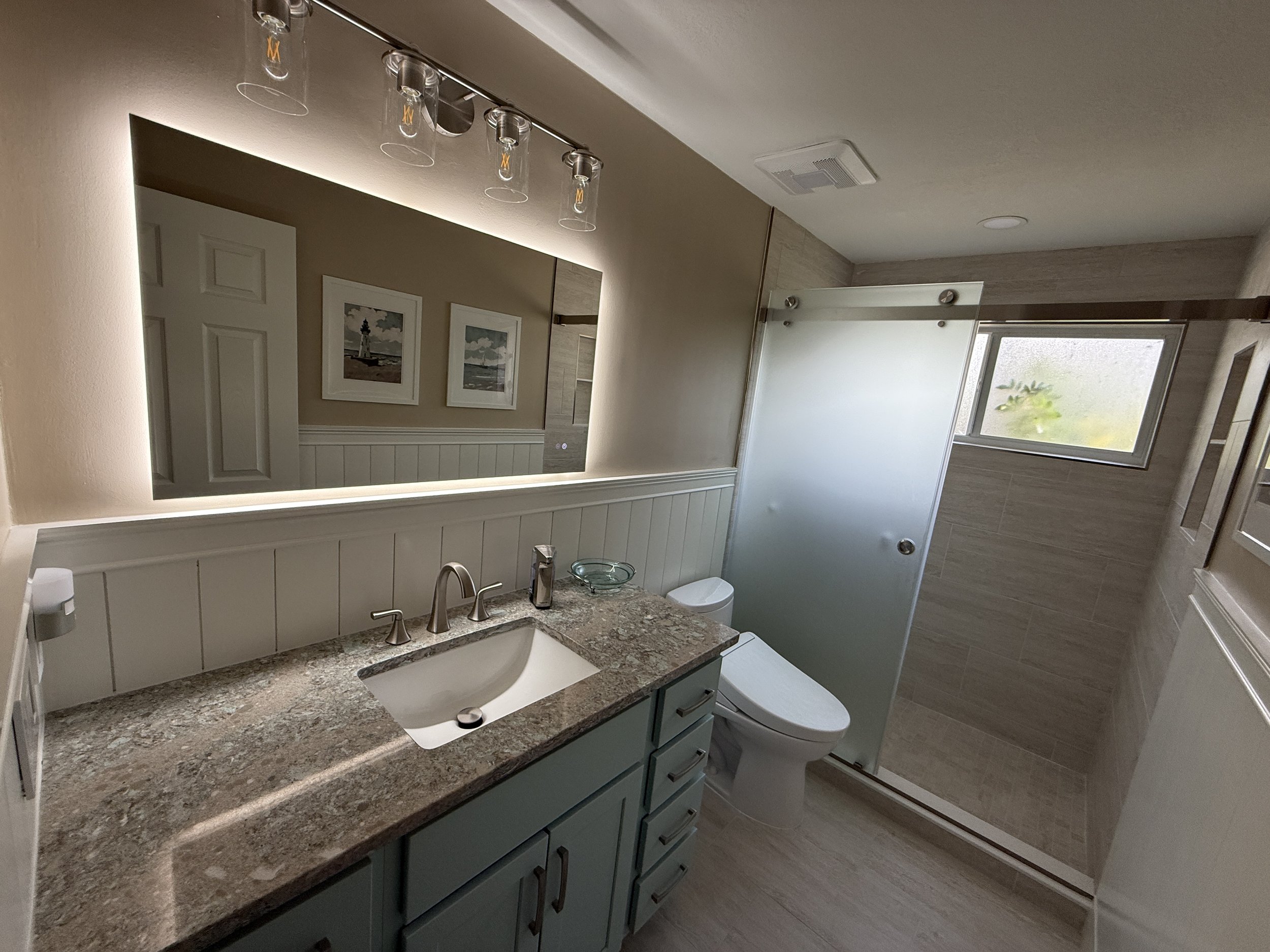 A bathroom remodel with a high end quarts countertop, a custom frosted glass enclosure . New tile floor, custom built shower and tile job. Built in tiled niche, new smart toilet with bidet that we complete in 2025 in Ormond Beach Florida 