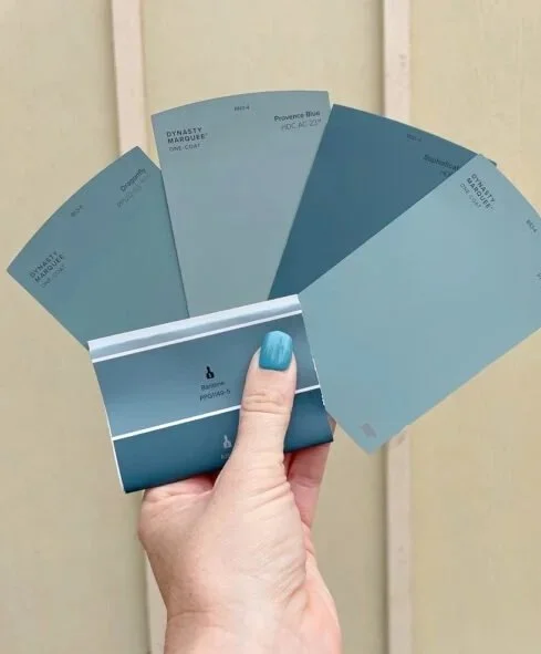 A hand holding five paint color swatches to show we care about your paint selections and can assist with selections and offer samples