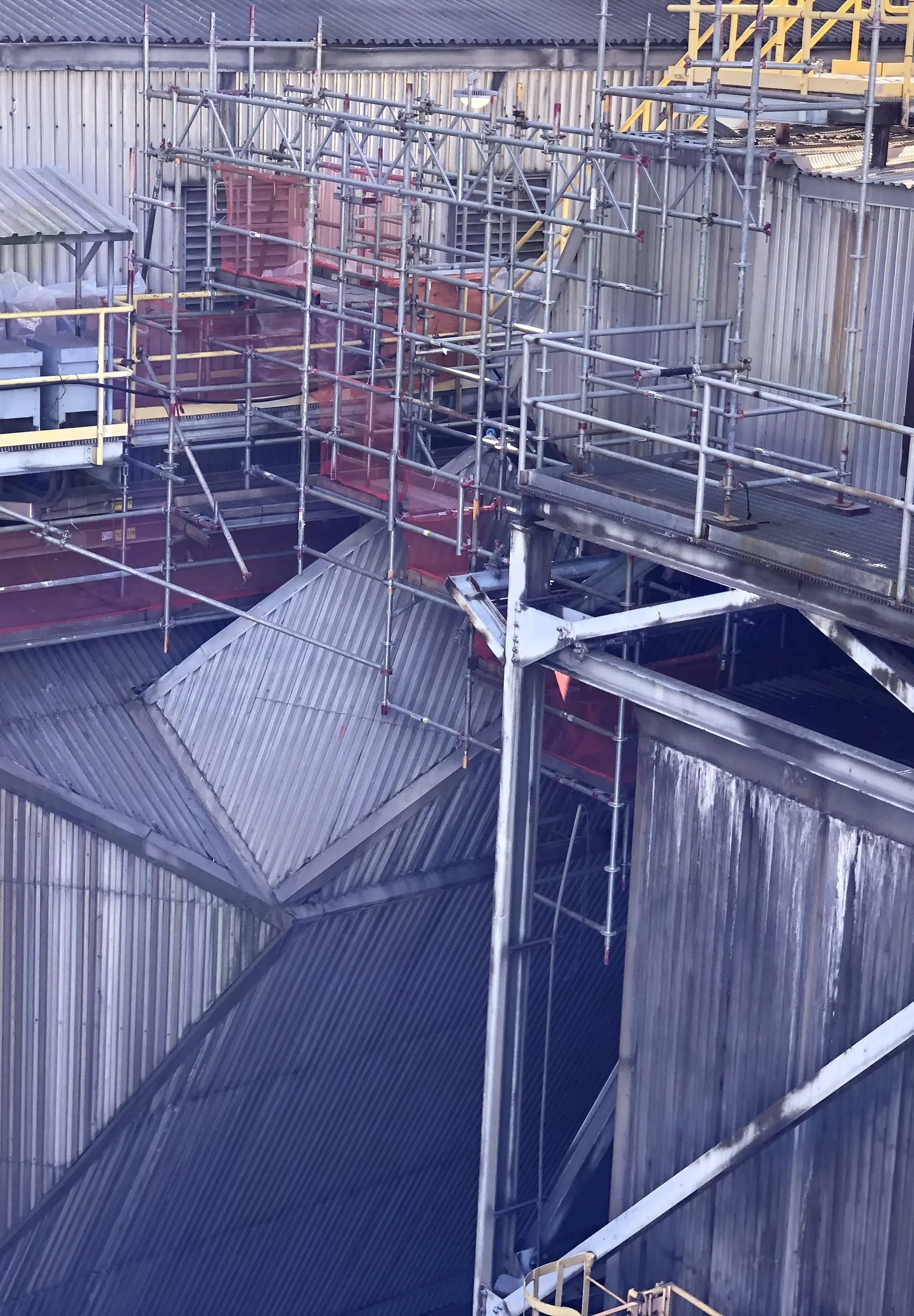 Construction site with metal scaffolding and corrugated metal walls.