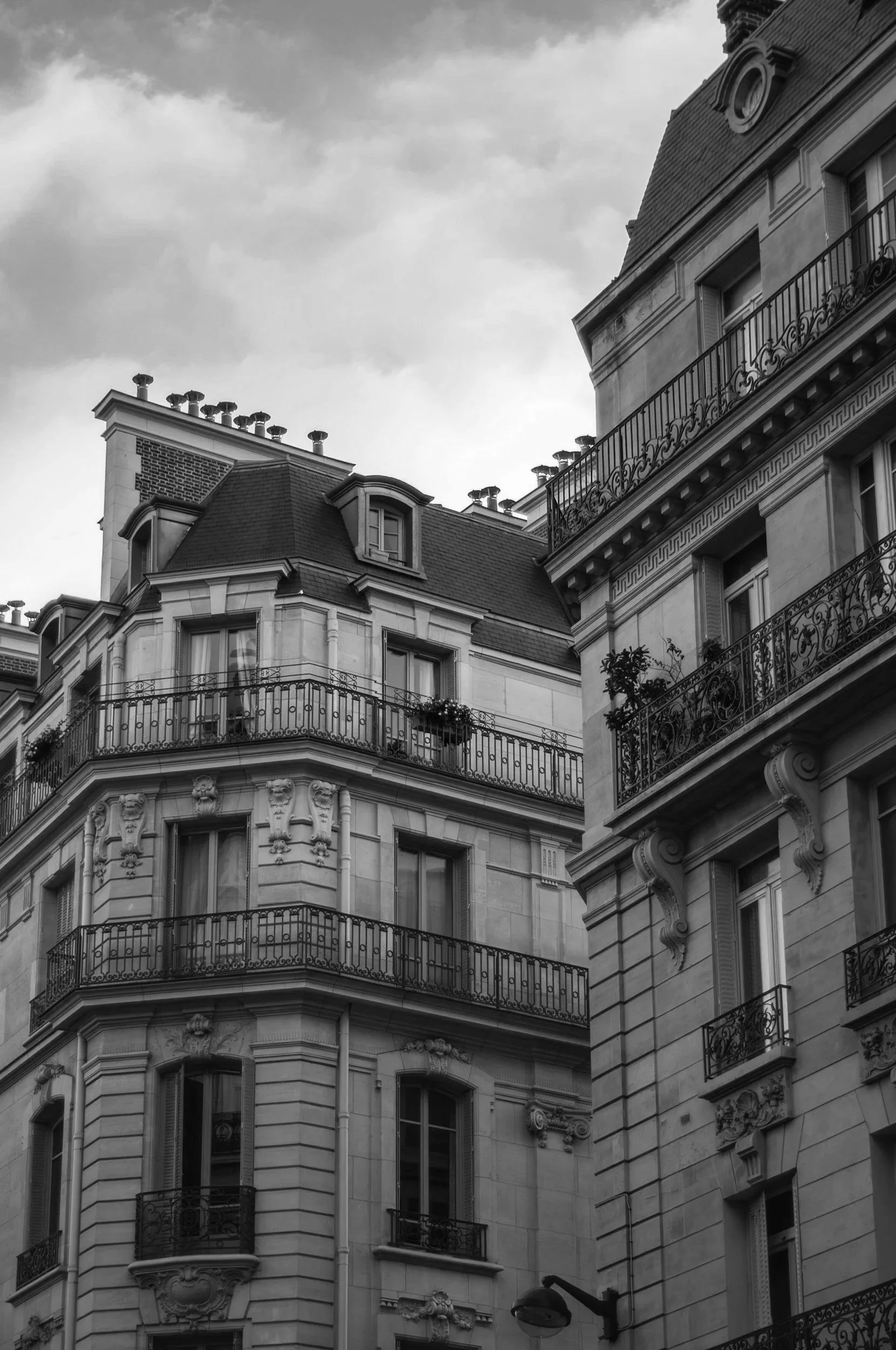 Black and white photo of classic Parisian apartment building with ornate balconies and mansard roof.