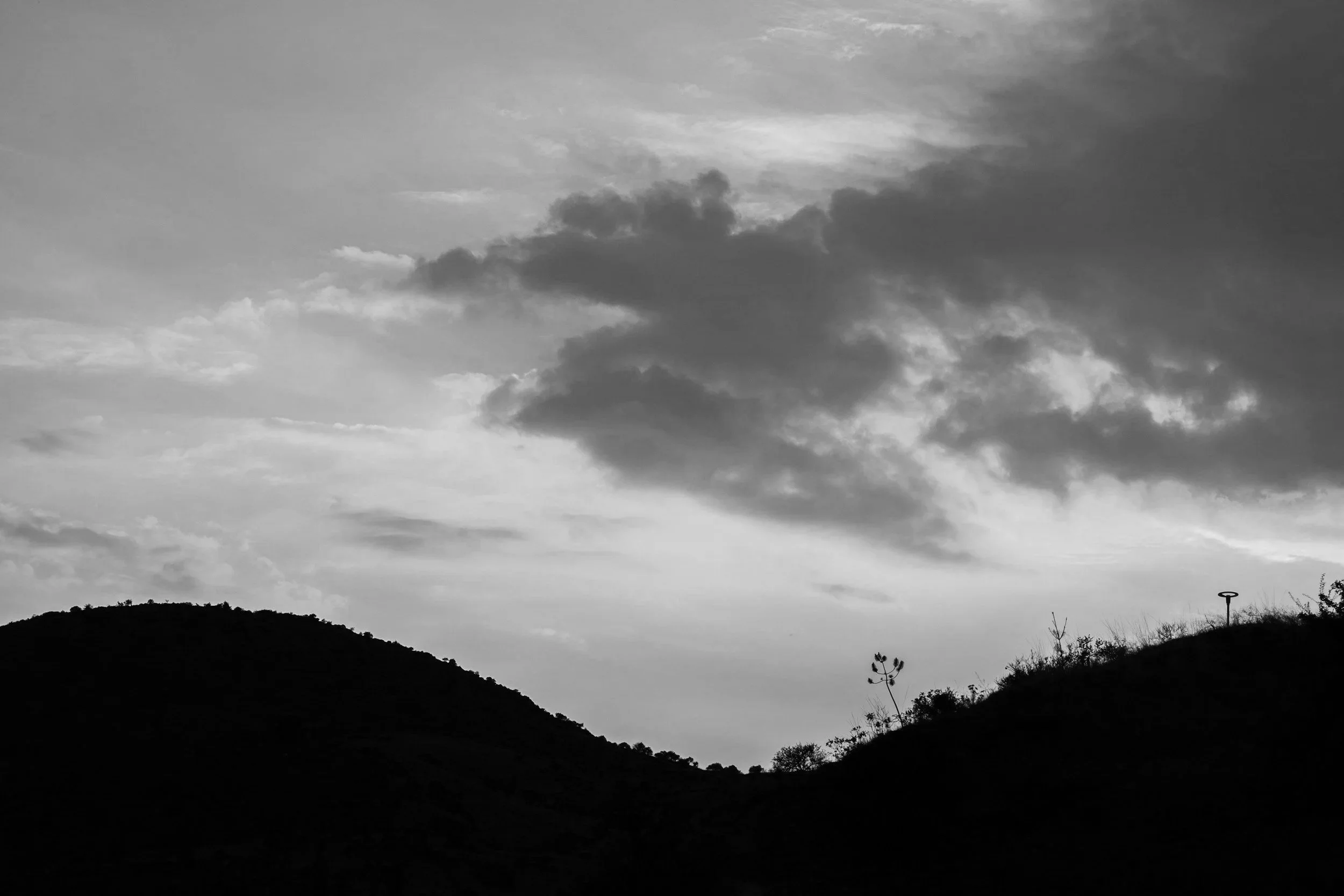 Black and white photo of hills with a cloudy sky.