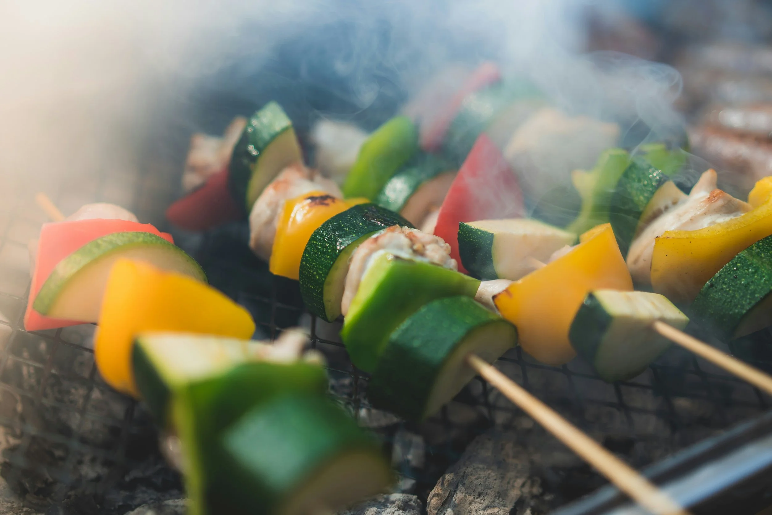 Brochettes de légumes grillés sur un barbecue avec de la fumée.
