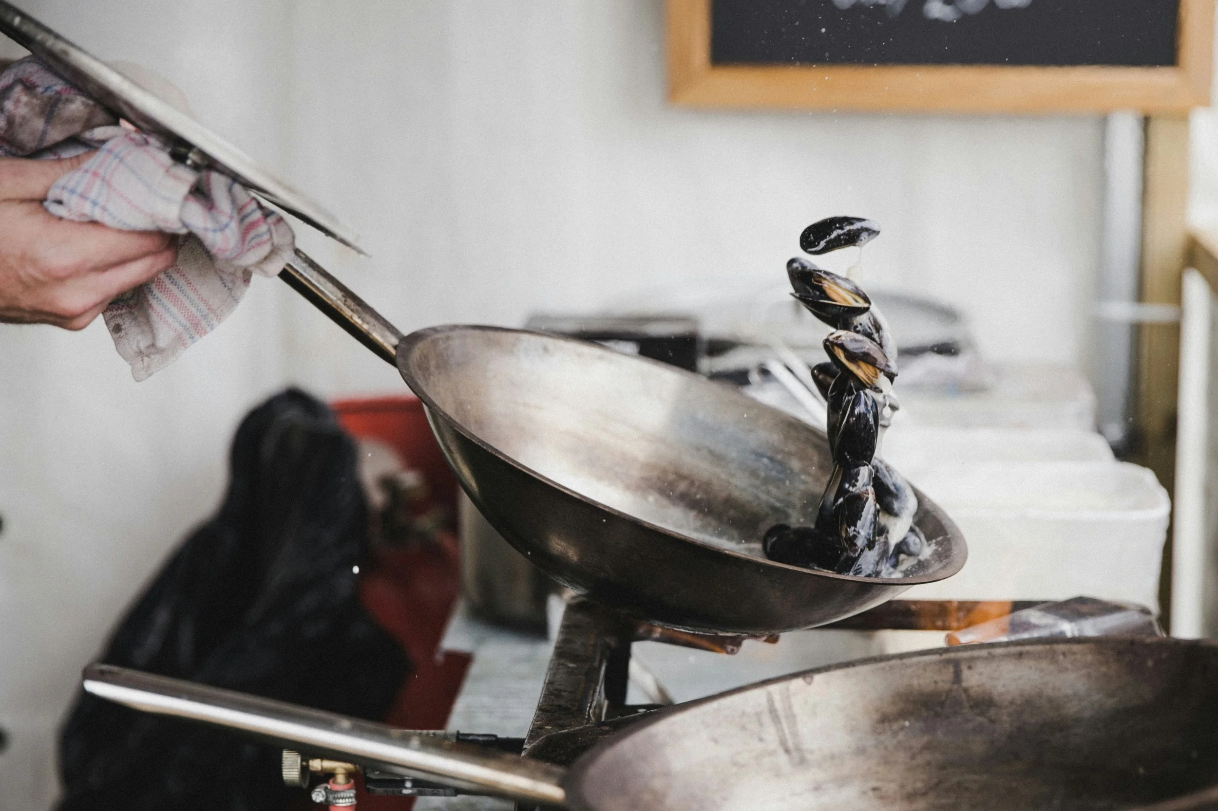 Cuisinier faisant sauter des moules dans une poêle à frire