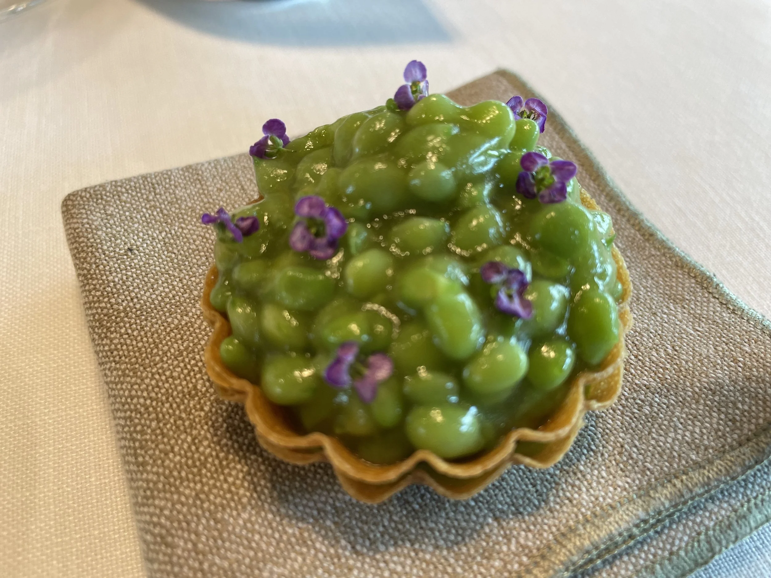 Tartelette aux groseilles vertes garnie de petites fleurs violettes.