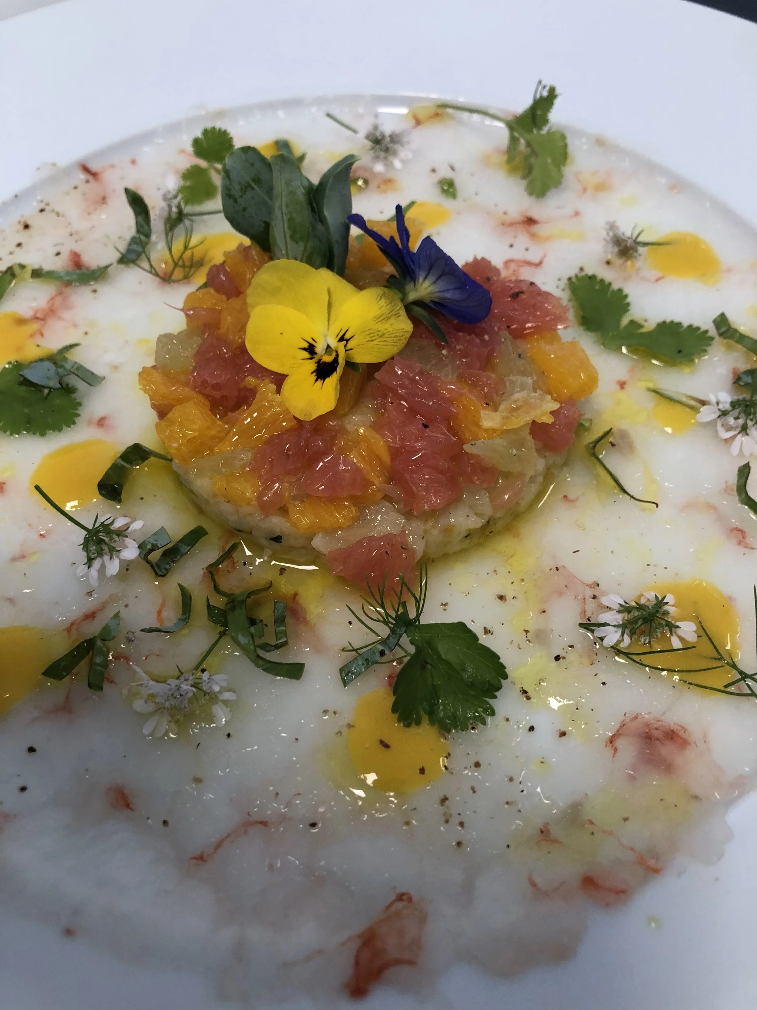 Oeuf cocotte avec une garniture de citron, de poisson, de fleurs comestibles et de herbes, décoré de fleurs et d'herbes fraîches.