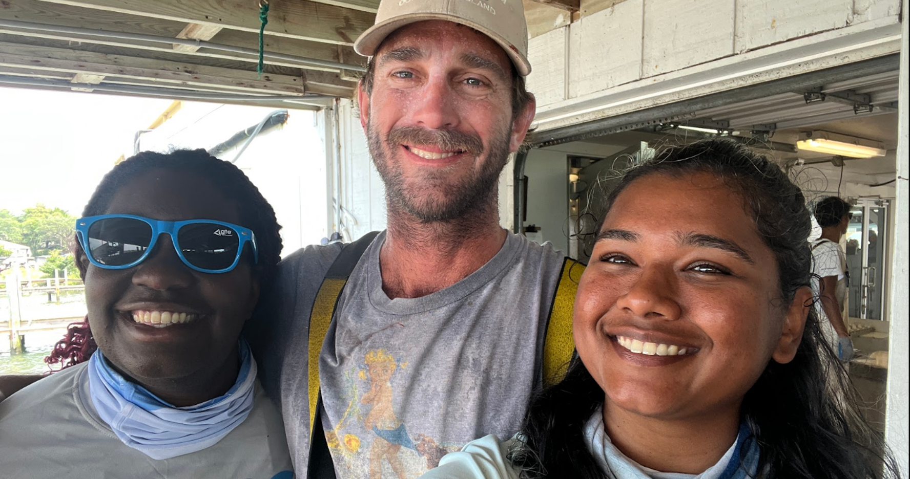Image showing Jasmin and another scientist standing on either side of a fisher named Dylan